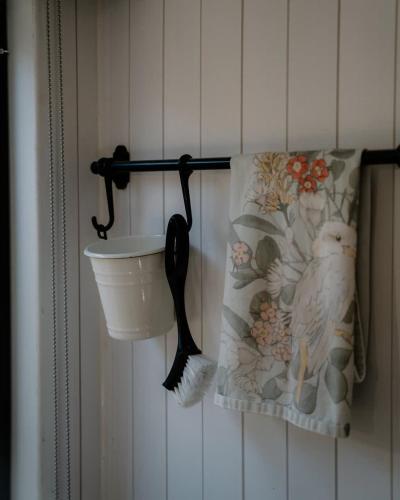 a bathroom wall with a toilet brush and a towel at Banyula Cove by Tiny Away in Barnes Bay