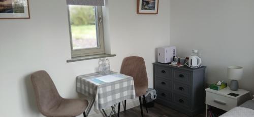 a bedroom with two chairs and a dresser and a window at Cozy Double Ensuite Room in Ennistymon