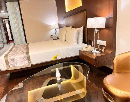 a hotel room with a bed and a glass table at Cocoon Luxury Business Hotel in Dhanbād