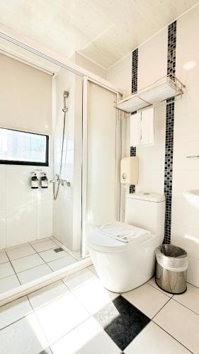 a white bathroom with a toilet and a shower at San Juan Easy Stay Inn Tainan in Tainan