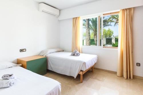 two beds in a room with a window at Villa Carousel in Benidorm