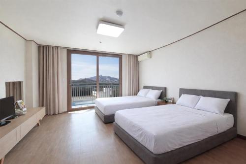 a hotel room with two beds and a large window at Ilsung Resort Sulak in Goseong