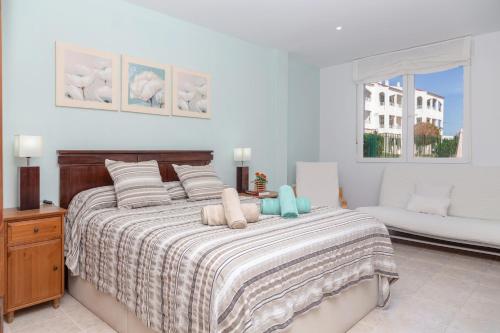 a bedroom with a bed and a couch and a window at Apartamento en Cala'n Blanes in Ciutadella