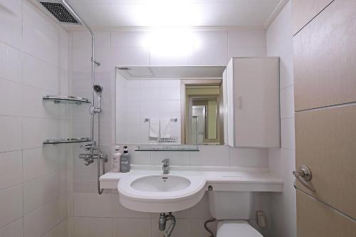 a white bathroom with a sink and a mirror at Ilsung Resort Sulak in Goseong