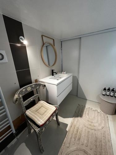 a bathroom with a sink and a chair and a mirror at Pause confortable, escapade culturelle in Caen