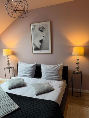 a bedroom with a large bed with two lamps at Apartament Umami in Pniewy