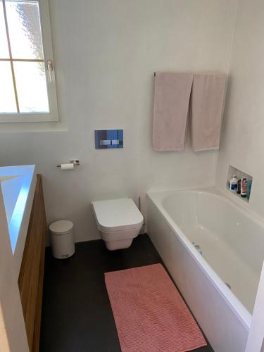 a bathroom with a tub and a toilet and a sink at Tierparkunterkunft in Goldau