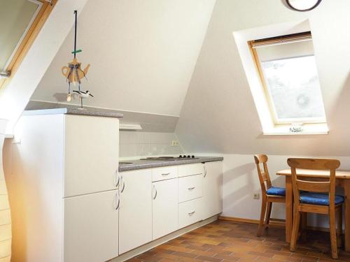 a kitchen with white cabinets and a table and a window at Gaestehaus-W-13 in Prerow