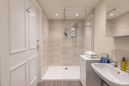 a white bathroom with a shower and a sink at The Hat Shop in Hexham