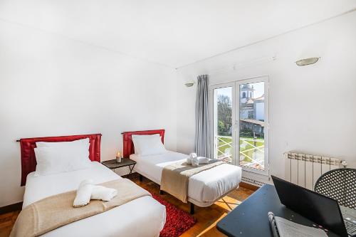 a bedroom with two beds and a desk with a laptop at HI Ofir – Pousada de Juventude in Esposende