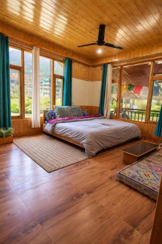 a bedroom with a bed in a room with windows at Ghar Homestay in Kulu