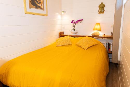 a yellow bed with two pillows in a room at Les Colombes in Saint-Tricat