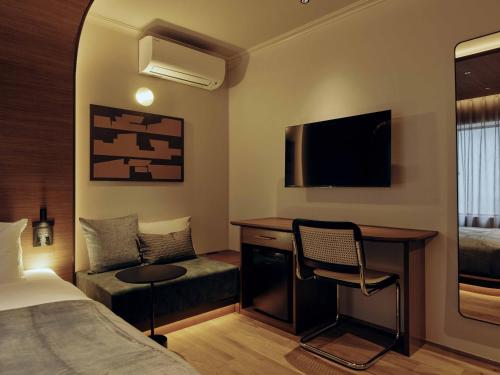a hotel room with a bed and a desk and a tv at illi Hotels Lume Shibuya in Tokyo