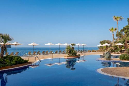 a swimming pool with umbrellas and a beach at Iberostar Selection Jardín del Sol Suites - Adults Only in Santa Ponsa
