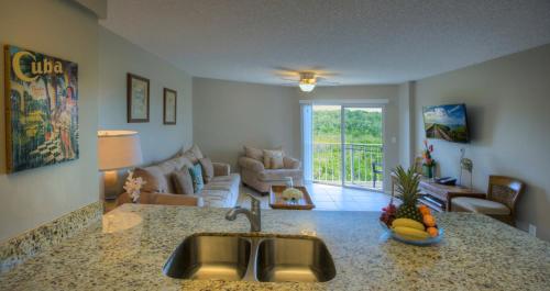 a kitchen with a sink and a living room at Ocean Pointe Suites at Key Largo in Key Largo