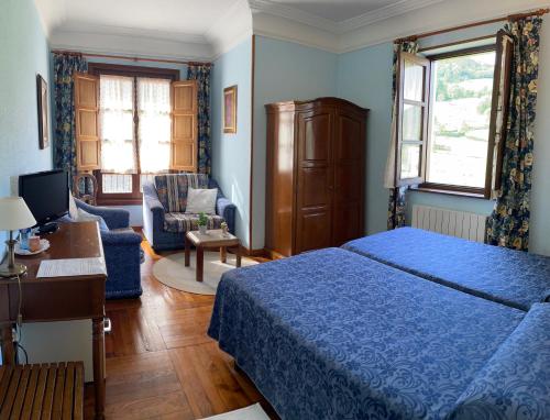 a bedroom with a blue bed and a desk at Hotel Rural Villa Elena in Panes