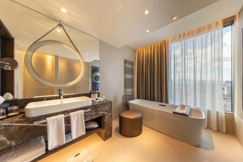 a bathroom with a tub and a sink and a mirror at InterContinental - Ljubljana by IHG in Ljubljana