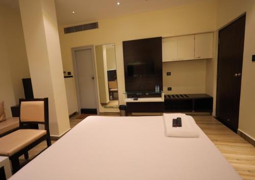 a room with a large white bed and a kitchen at YAR INN CENTRAL in Vijayawāda