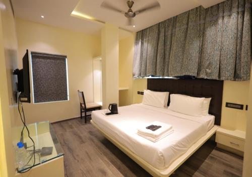 a bedroom with a large white bed with a television at YAR INN CENTRAL in Vijayawāda