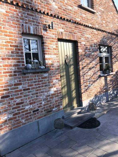 a brick building with two chairs in front of a door at L'enjo'Leuze in Winée