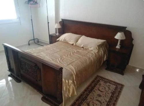a bedroom with a large wooden bed and two lamps at Apartment Centre Hamria in Meknès