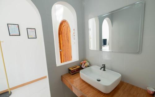 a bathroom with a white sink and a mirror at Baan Iris Salaya in Salaya