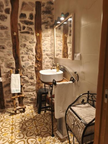 a bathroom with a sink and a stone wall at Casa Sorianna in Montenegro de Cameros