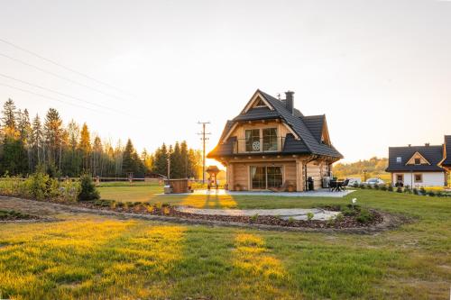 a house sitting on top of a lush green field at Jagodowa Osada - domki z balią z hydromasażem blisko term in Dzianisz