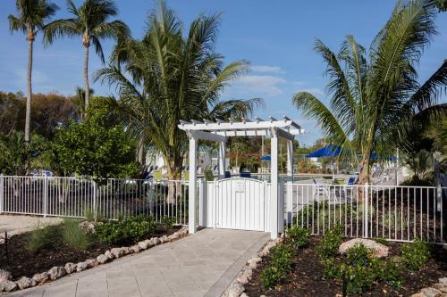 a white fence with a gate and palm trees at Ocean Pointe Suites at Key Largo in Key Largo