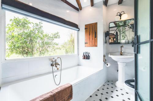 a bathroom with a tub and a sink and a window at Moon River Village in Ban Bu Khanun