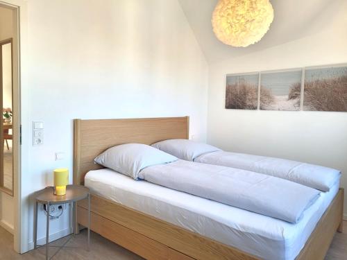 two beds in a room with a table and a chandelier at Heiligenhafenbude 2 in Heiligenhafen