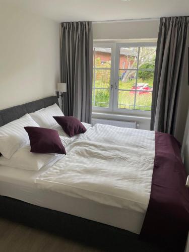 a large bed in a bedroom with a window at Seaside-Amrum-6 in Norddorf