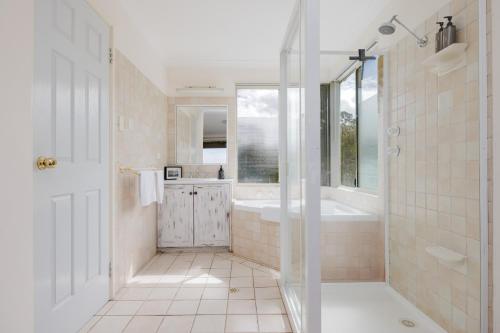 a bathroom with a shower and a tub and a sink at Surfside Ocean Beach Denmark Holiday Accommodation in Denmark