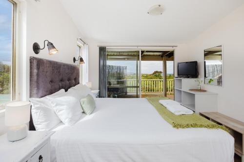 a white bedroom with a large bed and a balcony at Surfside Ocean Beach Denmark Holiday Accommodation in Denmark