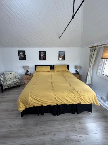 a bedroom with a large bed with a yellow bedspread at Woodland Chalet at Otters Green in Botley