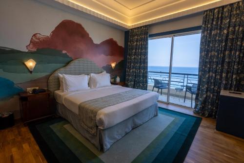 a bedroom with a bed with a view of the ocean at Warwick Palm Beach Hotel in Beirut