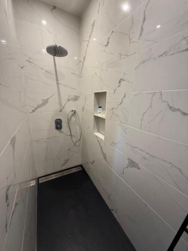 a bathroom with a shower with white marble walls at La Loge 45 in Rodez