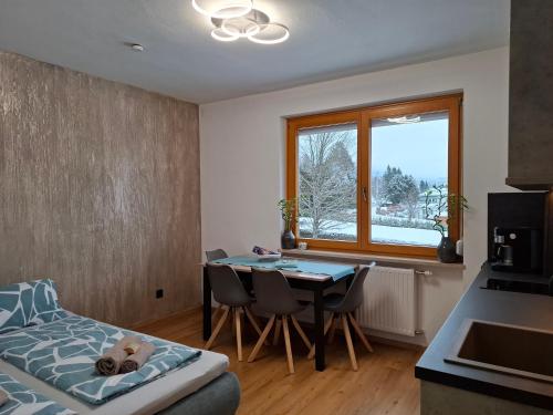 a bedroom with a table and a bed and a window at FEWO Erika in Presseggen