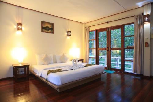 a bedroom with a large bed and a large window at Barn Talaepu Resort in Ban Suan Khat