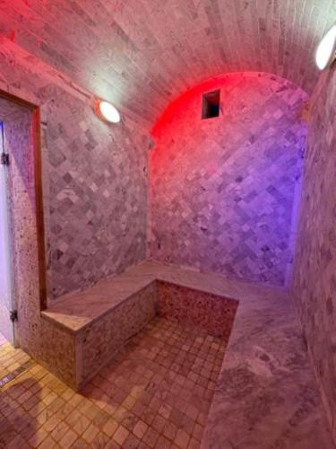 a stone shower with a bench in a room with a red light at Houch Ennejma in Al Ḩārah al Kabīrah