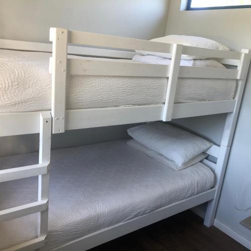 a bunk bed with white bunk beds in a room at Plett Pods - Casetta del Fuoco - Eco Container Cottage in Plettenberg Bay