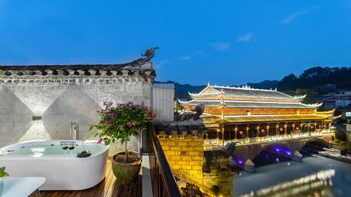 a bath tub on a balcony next to a building at Phoenix River View Hotel-Free pick up service from Railway in Fenghuang County