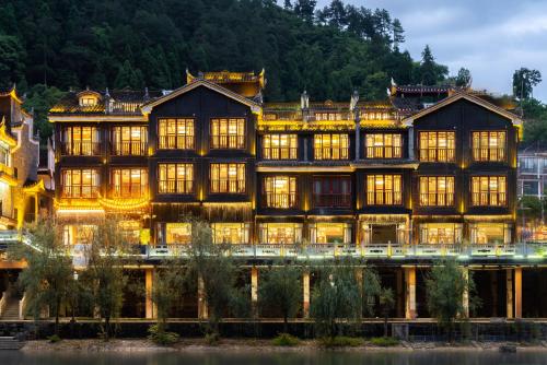 a large building with many windows on the water at Phoenix River View Hotel-Free pick up service from Railway in Fenghuang County