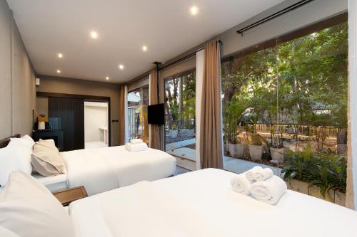 a bedroom with two beds and a large window at OHASIS by OH Hotels in Bangkok