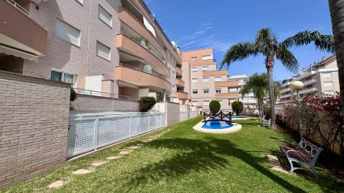 a garden with a bench and palm trees and buildings at Residencial Ronda Mar in Denia