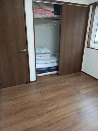 a room with a closet with a door and a wooden floor at ミエル富士 in Oishi