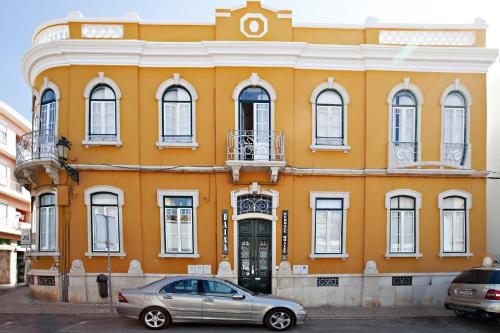 a yellow building with a car parked in front of it at Baixa Terrace Hostel in Faro