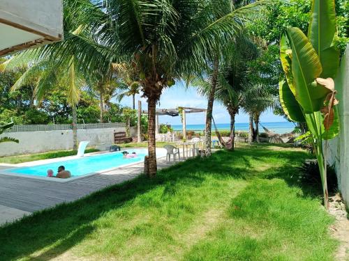 a resort pool with palm trees and people swimming at Kitnet com veranda in Conde