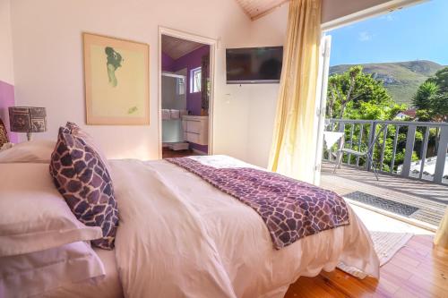 a bedroom with a bed and a balcony with a television at Airconditioned Apartment for 3 guests. in Hermanus