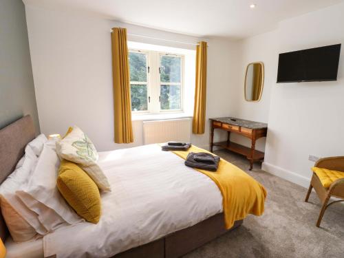 a bedroom with a bed with a television and a desk at Stewards House in Tadcaster